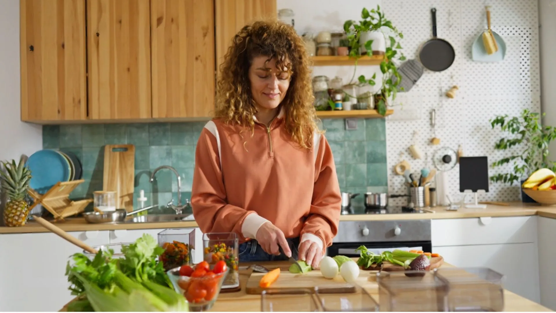 Vrouw snijdt groente in een lichte keuken met meal-prep bakjes